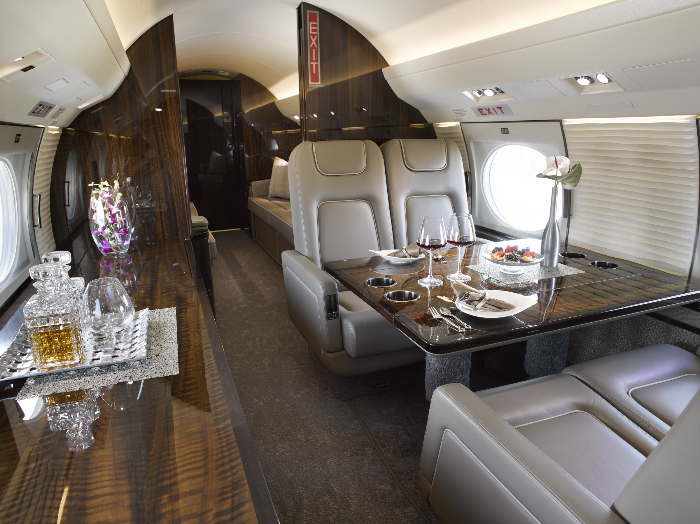 Business jet cabin with cream leather seating and a polished wood table.
